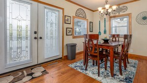 A dining area with a wooden table and chairs, a chandelier, and a rug.