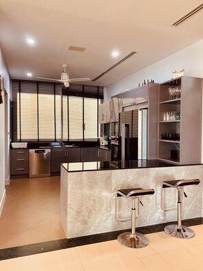 A modern kitchen with a central island, bar stools, and a built-in wine rack.