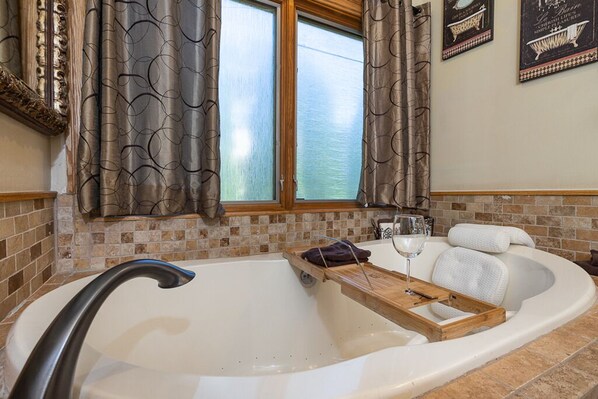 A modern bathroom with a freestanding bathtub, a wooden tray, and a glass of wine.