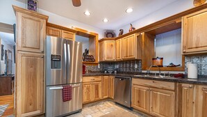 A modern kitchen with wooden cabinets, stainless steel appliances, and a tiled backsplash.