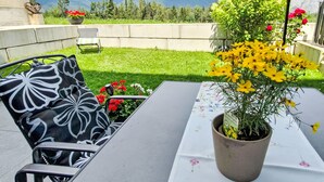 A patio with a table, chairs, and a potted plant with yellow flowers. - Apartment Sabine by Interhome (Oberperfuss)