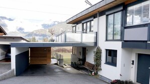 A modern two-story house with a covered driveway, large windows, and a view of mountains. - Apartment Sabine by Interhome (Oberperfuss)