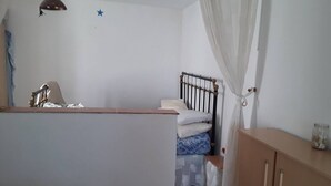 A bedroom with a bed, a wooden wardrobe, a nightstand, and a ceiling fan.