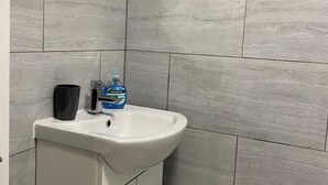 Une salle de bain avec un lavabo blanc, une tasse noire et une bouteille de savon Palmolive.