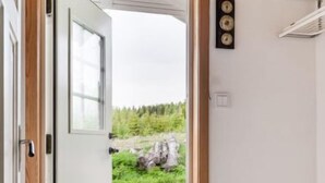 A room with a wooden door leading to a grassy outdoor area.