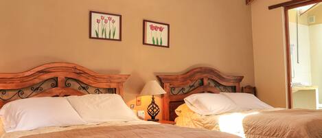 A bedroom with two wooden beds, a wooden ceiling with exposed beams, and a chandelier.