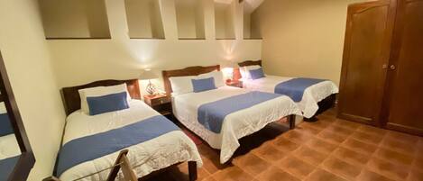 A room with three beds, wooden beams on the ceiling, and a tiled floor.