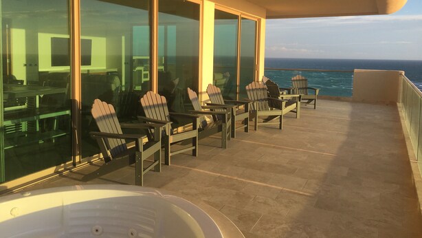 Un balcone con sedie e una vasca idromassaggio, con vista sull'oceano.