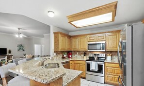 A modern kitchen with granite countertops, stainless steel appliances, and wooden cabinetry.