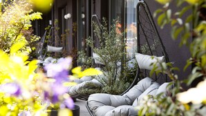 A seating area with cushioned chairs and a table, surrounded by plants and flowers. - Hotel Indigo Vienna – Naschmarkt by IHG (Vienna)