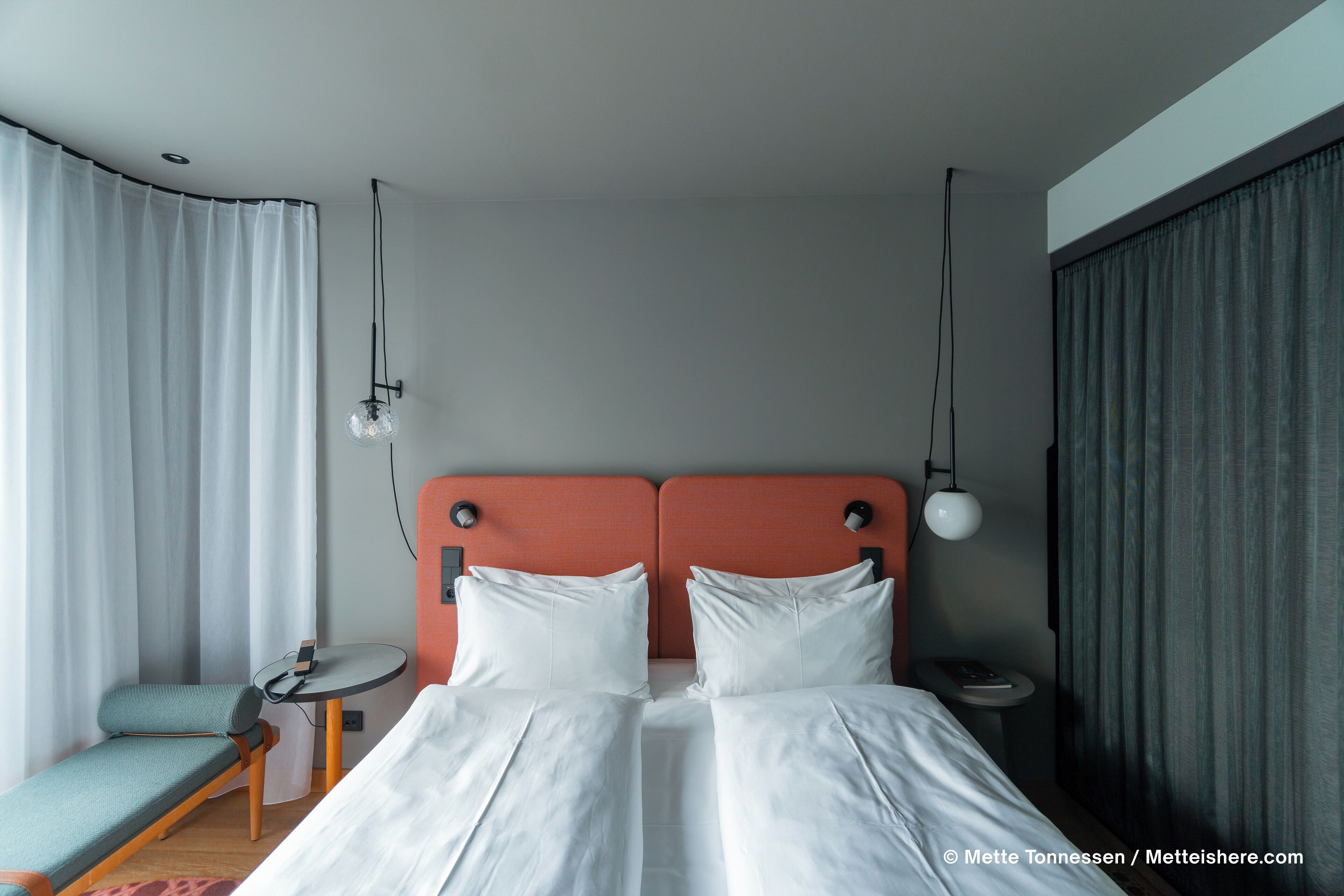 Una habitación de hotel con una cama doble, una mesita de noche pequeña, una silla y un escritorio.