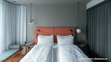 Una habitación de hotel con una cama doble, una mesita de noche pequeña, una silla y un escritorio.