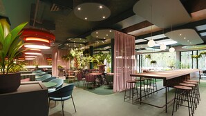 A modern interior with round tables, bar stools, and green chairs. - Hotel Indigo Vienna – Naschmarkt by IHG (Vienna)