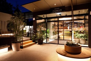 The exterior of Hotel Indigo with large potted plants, a modern entrance, and a visible bar area inside. - Hotel Indigo Vienna – Naschmarkt by IHG (Vienna)