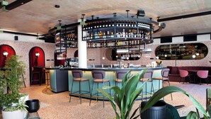 A bar area with a circular bar counter, multiple seating options, and a variety of plants. - Hotel Indigo Vienna – Naschmarkt by IHG (Vienna)