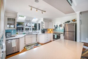 A modern kitchen with white cabinetry, stainless steel appliances, and a large island.