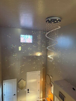 A room with a ceiling light fixture, a wall-mounted projector, and a door. - Modern and cozy three bedroom townhome (Hurricane)
