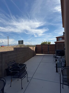 An outdoor patio with a concrete floor, metal chairs, a wooden gate, and a view of a distant landscape. - Modern and cozy three bedroom townhome (Hurricane)