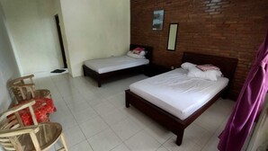 Una habitación con dos camas, una silla de madera y una pared de ladrillo.