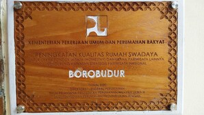 Una placa de madera con texto en relieve y un logotipo, montada en una pared.