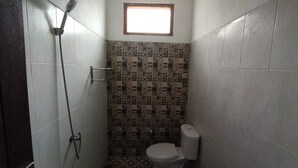 Un baño pequeño con azulejos, ducha, inodoro y una ventana sobre el lavamanos.