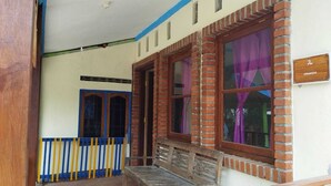 Una habitación con un banco de madera, una ventana con cortinas moradas y una pared de ladrillo.