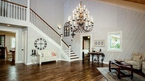 A spacious loft with a high ceiling, a grand chandelier, a staircase, and a cozy seating area. - Beautiful Farmhouse with serene environment. 4+ acres beautiful landscape. 
 (Wallis)