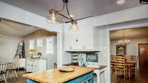 A kitchen with wooden flooring, a blue table, and white cabinetry. - Beautiful Farmhouse with serene environment. 4+ acres beautiful landscape. 
 (Wallis)