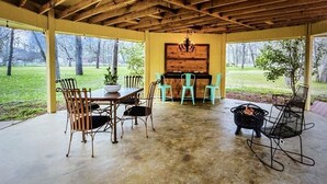 An outdoor covered patio with a wooden ceiling, a grill, and seating. - Beautiful Farmhouse with serene environment. 4+ acres beautiful landscape. 
 (Wallis)