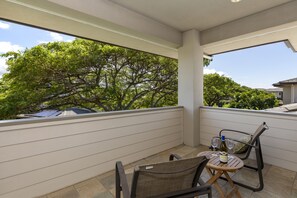 Ein Balkon mit Tisch, zwei StĂŒhlen und einer Weinflasche.