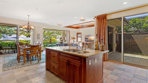A spacious kitchen with a large island, wooden cabinetry, and a dining area with a table and chairs.