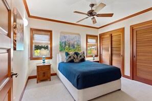 Ein Schlafzimmer mit einem Bett, einem Nachttisch, einem Deckenventilator und einem Fenster mit Jalousien.