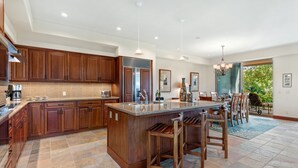 A spacious kitchen with wooden cabinets, a large island with bar stools, and a dining area with chairs.