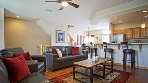 A modern living room with a sofa, coffee table, and a dining area with bar stools. - Close to 5 Ski Resorts - On Free Bus Route - Blue River in Backyard + Hot Tub (Silverthorne)