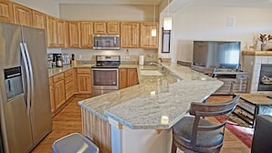 A modern kitchen with wooden cabinets, stainless steel appliances, a granite countertop, and a built-in oven. - Close to 5 Ski Resorts - On Free Bus Route - Blue River in Backyard + Hot Tub (Silverthorne)
