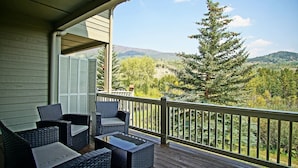A covered outdoor seating area with wicker furniture and a view of a forest and mountains. - Close to 5 Ski Resorts - On Free Bus Route - Blue River in Backyard + Hot Tub (Silverthorne)