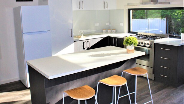 A modern kitchen with a central island, bar stools, a refrigerator, and a stove. - New, Modern Property built in 2021 * Close to Town (Glenroy)