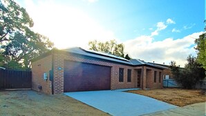 A single-story brick building with a garage, a covered driveway, and a fenced yard. - New, Modern Property built in 2021 * Close to Town (Glenroy)