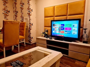 Relax in this stylish living room with a large flat-screen TV, comfortable armchair, and elegant coffee table.