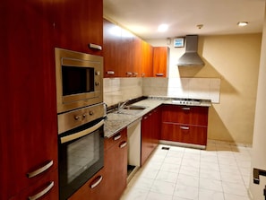 Kitchen features an oven, microwave, and stainless steel sink on a granite countertop.