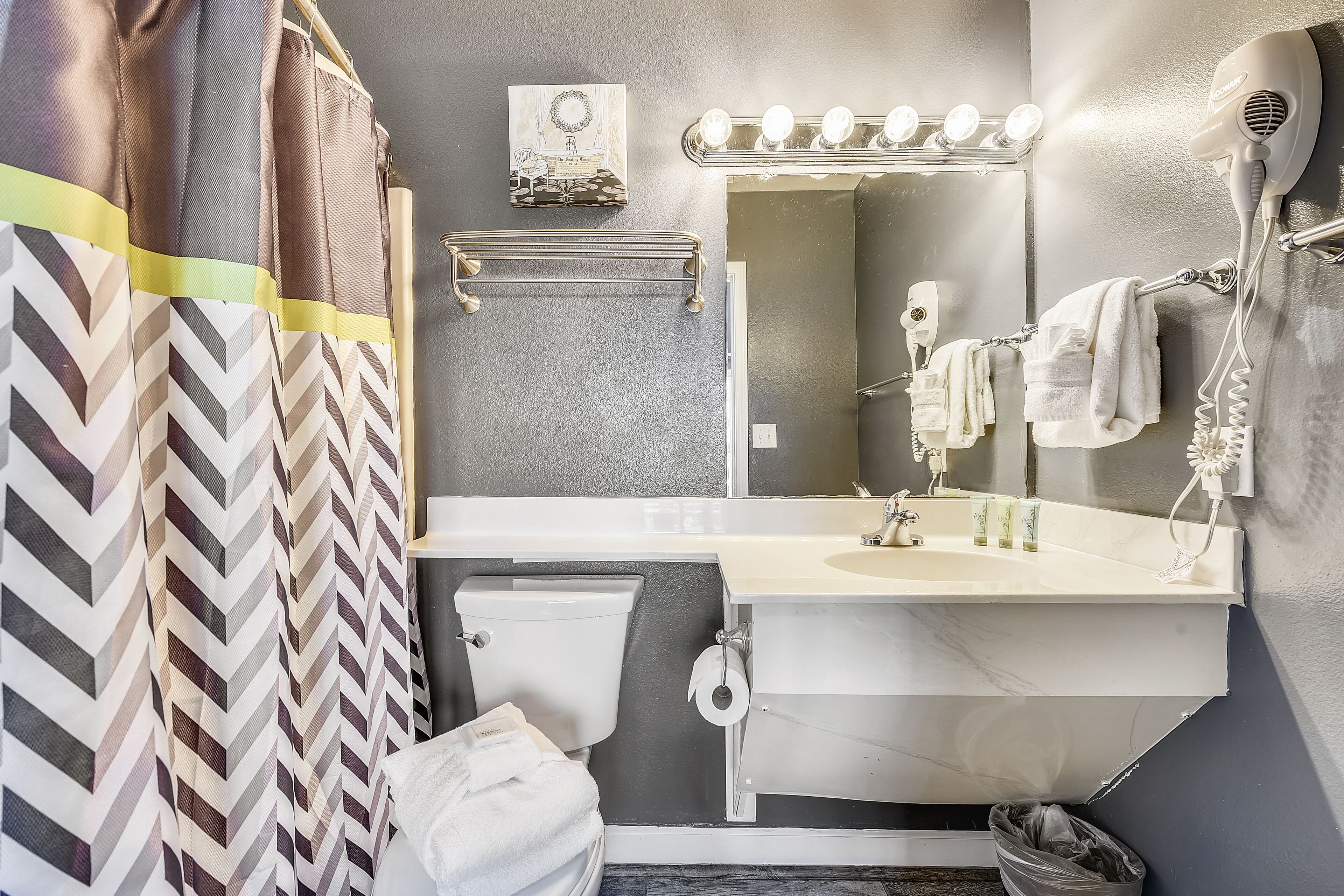 Un baño con espejo, tocador y cortina de ducha.