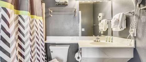 Un baño con espejo, tocador y cortina de ducha.