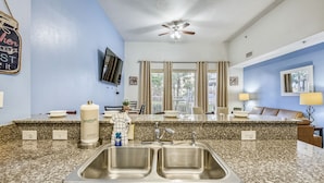 A kitchen with granite countertops, stainless steel sinks, and a ceiling fan.