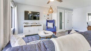 A modern living room with a ceiling fan, a blue armchair, a white sofa, and a coffee table. - Walk to Coligny Beach: Tropical Hilton Head Condo (Hilton Head Island)