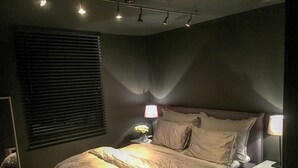 Une chambre à coucher avec un lit, des lampes de chevet, une table de chevet et une fenêtre avec des stores.