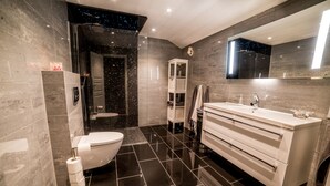 Une salle de bain moderne équipée de toilettes, d’un lavabo et d’un espace douche.