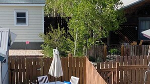 A patio with a table and chairs, a wooden fence, and a green artificial turf area.