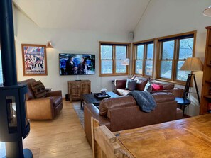 A cozy living room with a fireplace, a television, and large windows. - The Red Lady, Cute 2BD in Town! (Crested Butte)