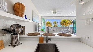 Uma cozinha moderna com uma janela grande, um ventilador de teto e vista para palmeiras.