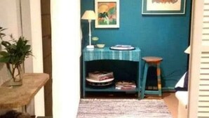 A narrow hallway with a teal wall, a small table with a lamp, a framed picture, and a shelf with books. - Holiday Home Mendoza Leisure Time (Luján de Cuyo)